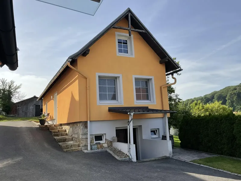 Eingangsseite des orangen Ferienhauses mit Stufen und Vordach