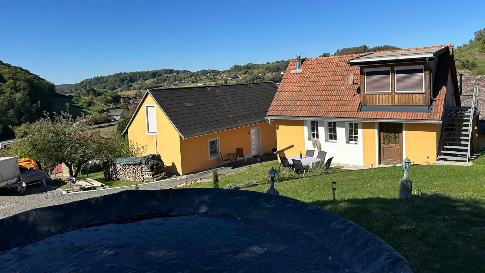Das gelbe Ferienhaus und das Nachbarhaus am Hang, dahinter das Tal